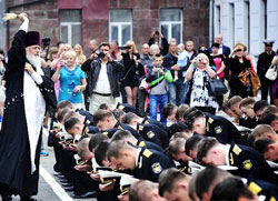 Фото, Владивосток. 21 июня 2012 года. 71-й выпуск офицеров ТОФ в ТОВМИ. Руководитель Отдела Владивостокской епархии по взаимодействию с Вооруженными силами РФ протоиерей Виктор Жильцов окропляет святой водой 175 коленопреклоненных лейтенантов